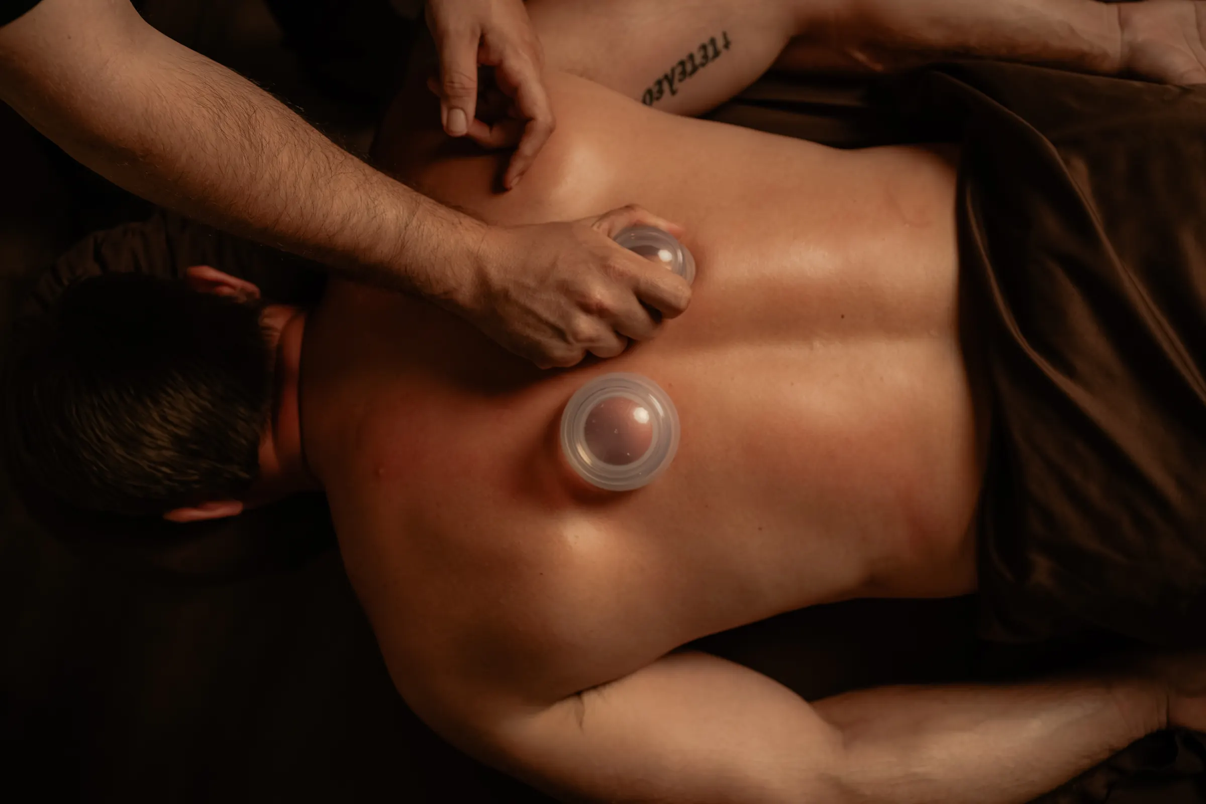 A Spavia massage therapist working around cupping cups on a guest's back