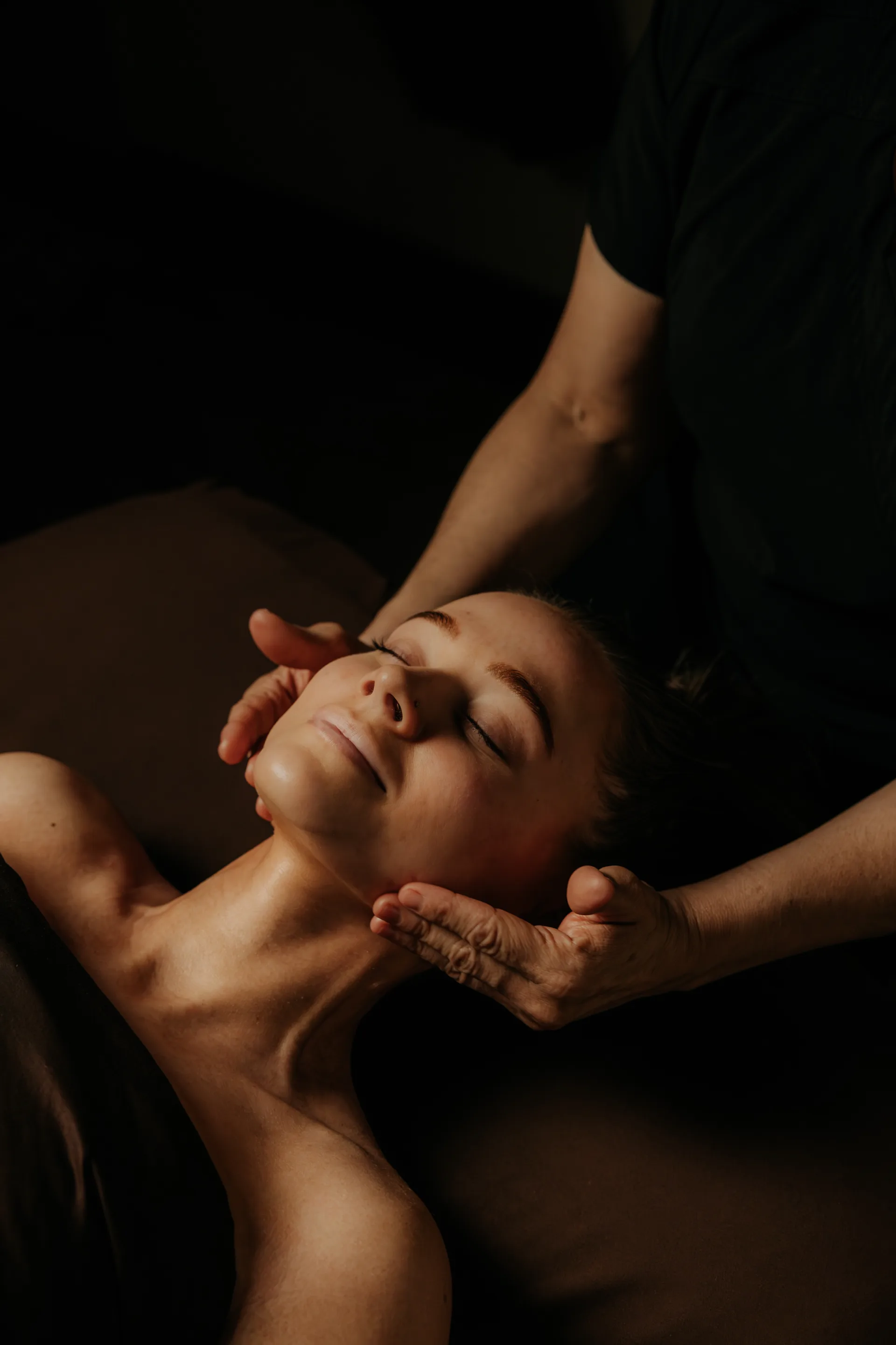 An esthetician giving a guest a facial massage by candlelight