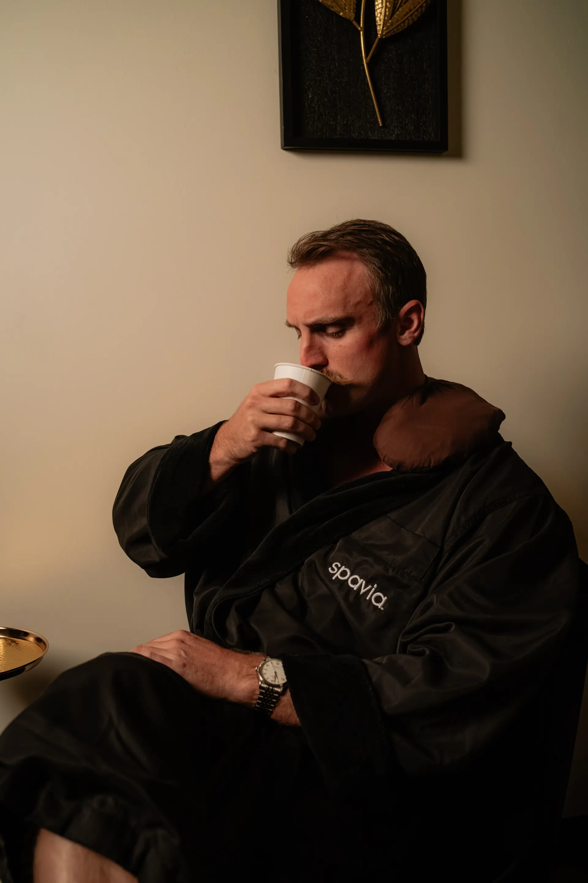 A male guest in a Spavia robe sipping a warm drink in the Retreat Room