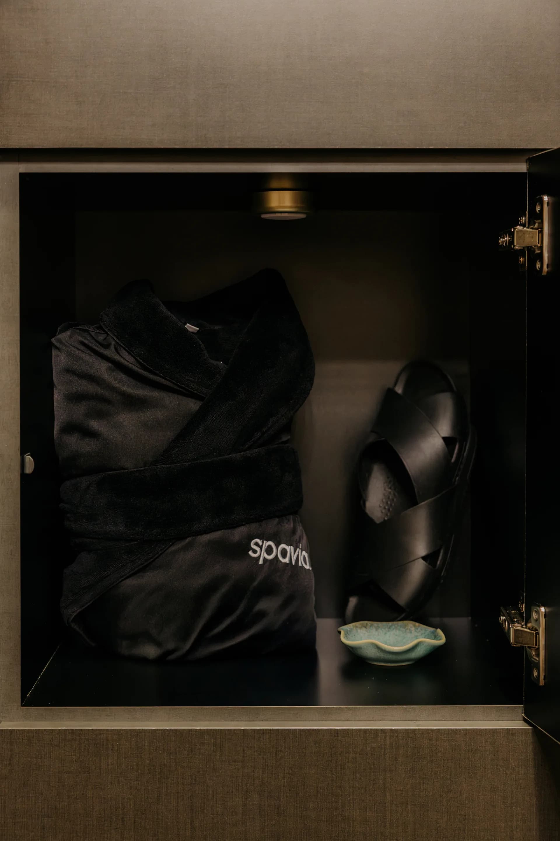 A folded Spavia robe and sandals waiting in a guest locker