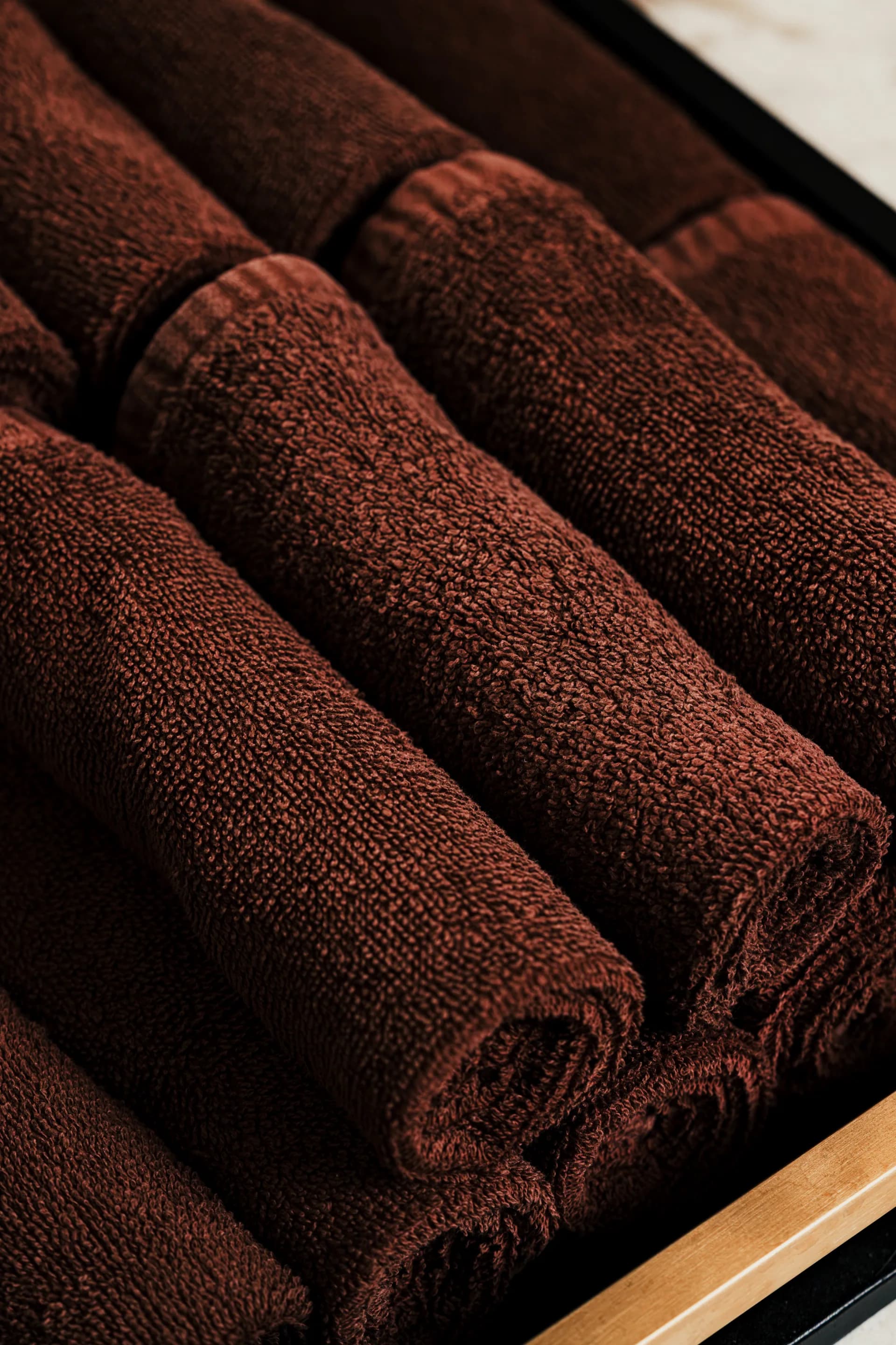 Rolled brown towels stacked on a shelf in a Spavia treatment room