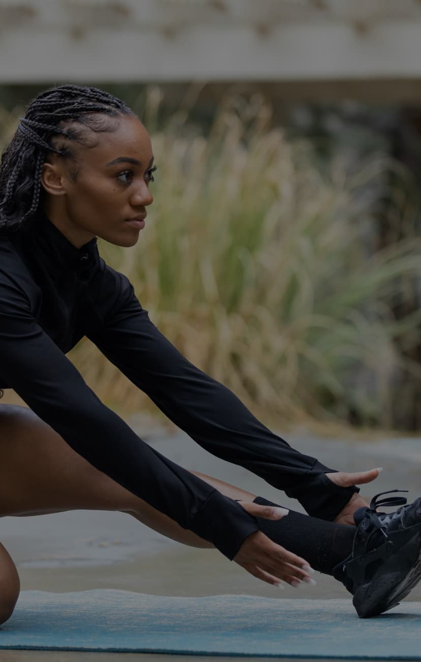 Person wearing a black shirt stretching with hands to thier feet