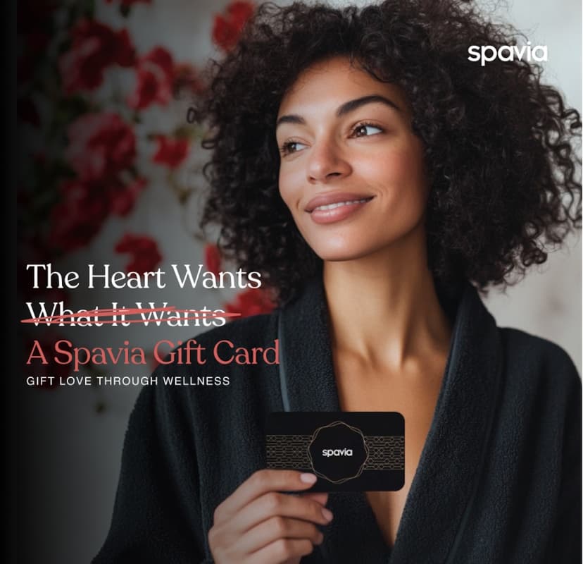 A happy woman in a robe holding a Spavia gift card
